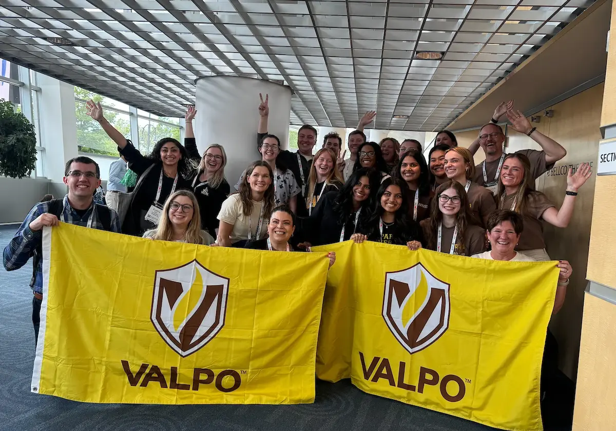 A group of students posing with 2 Valpo flags